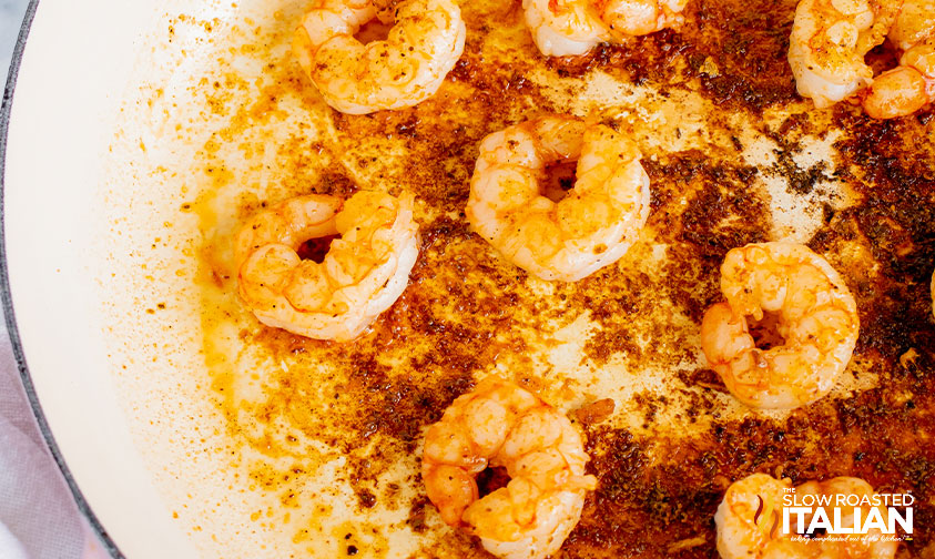 adding seasoning to shrimp in pan.