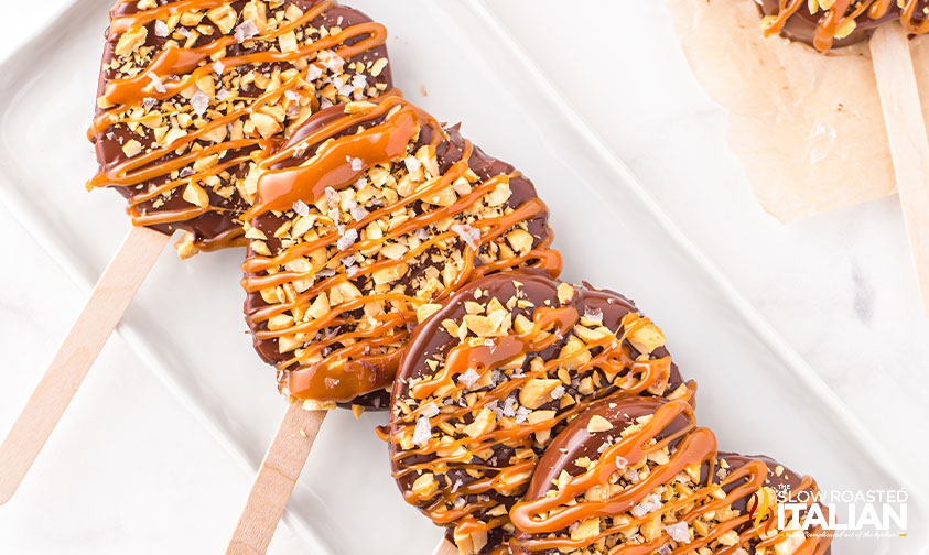 chocolate covered apple slices on white serving tray.