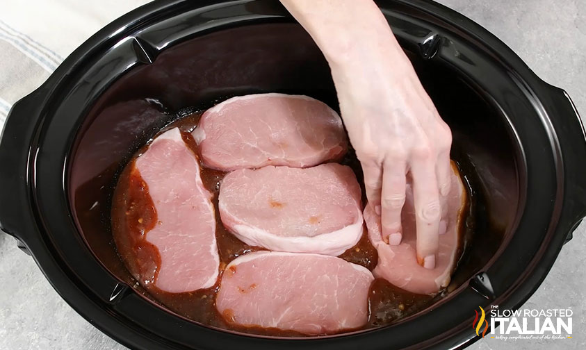 adding pork chops to crockpot.