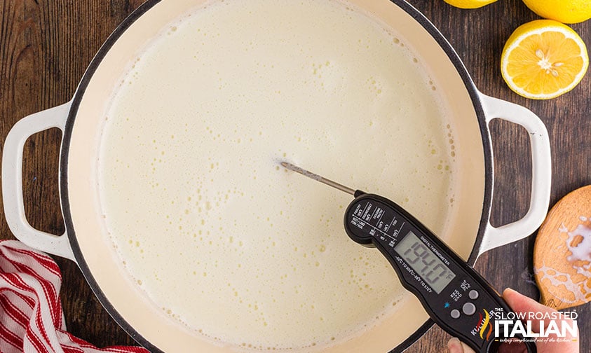 checking temperature of milk in pot.