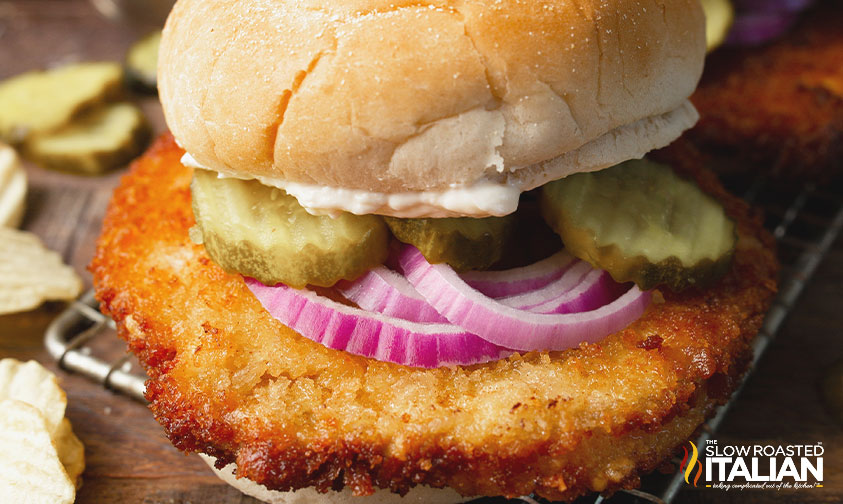 pork tenderloin sandwich with onion and pickles.