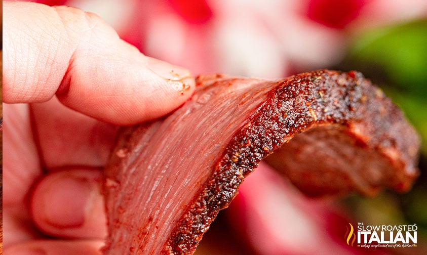 fingers holding strip of smoked roast beef.