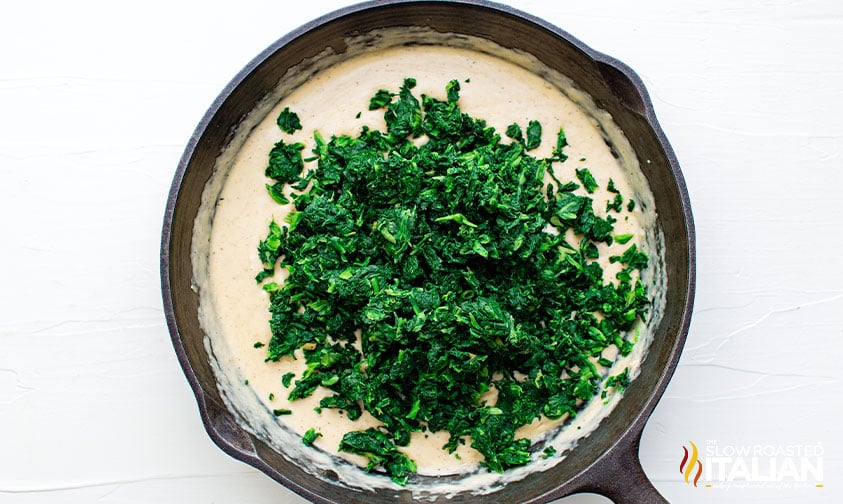 adding spinach to cream in skillet