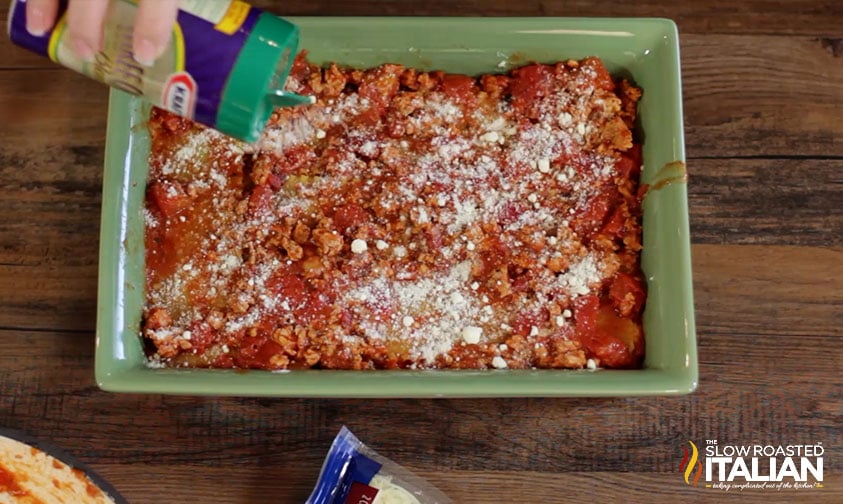 sprinkling cheese on italian sausage lasagna