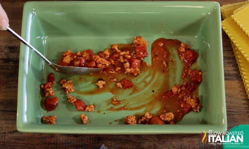 adding meat sauce to baking dish.