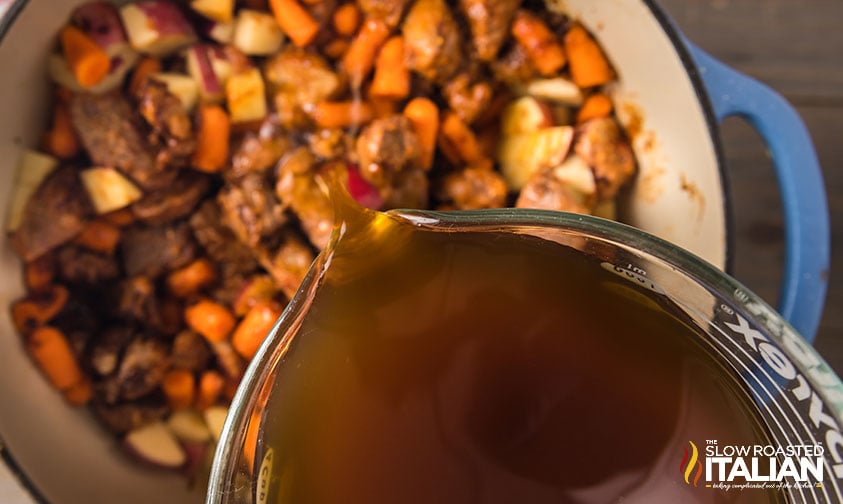 ouring broth into beef and veggies