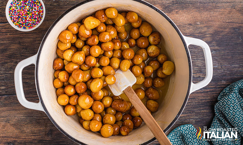 soaking struffoli in glaze.