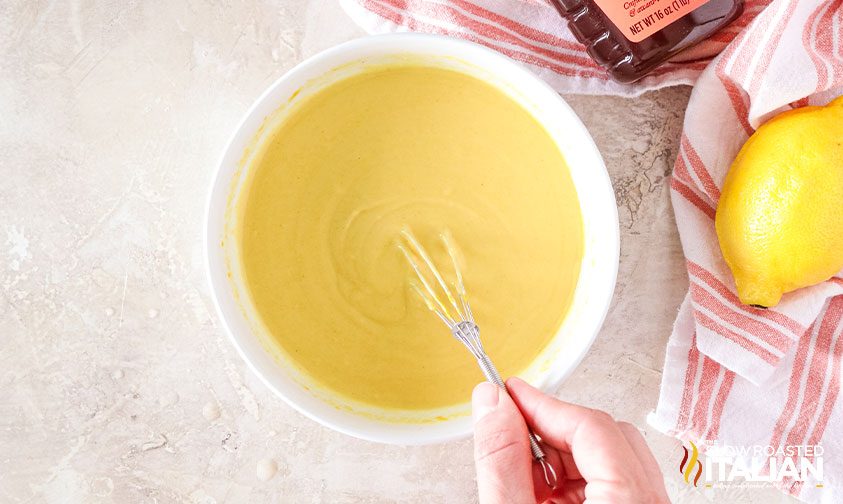 whisking honey mustard sauce in a white bowl