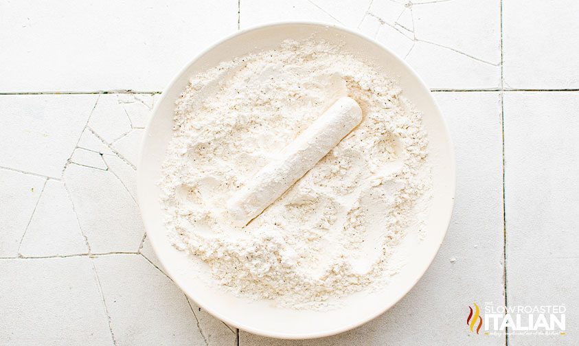 dredging mozzarella stick in seasoned flour
