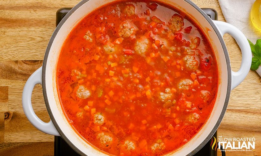 simmering a pot of Italian soup with meatballs