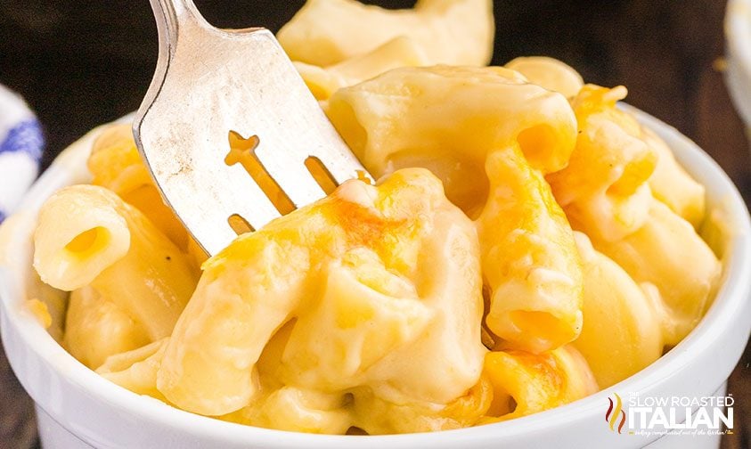 closeup: fork digging into ramekin of broiled mac and cheese