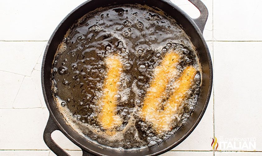 frying cheese sticks in a pot of oil
