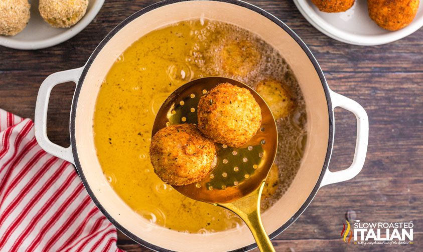 removing deep fried arancini from hot oil