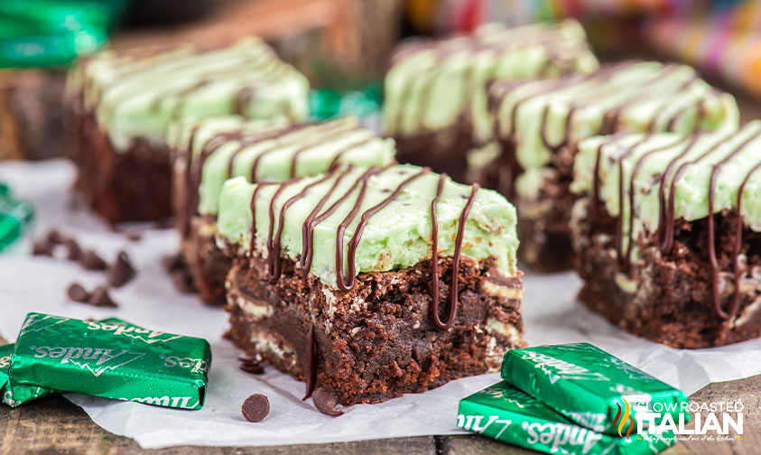 mint chocolate chip brownies topped with green frosting and chocolate drizzle
