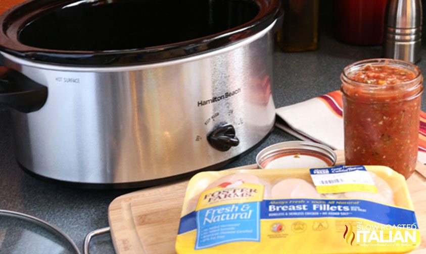 package of chicken breasts next to slow cooker and jar of salsa