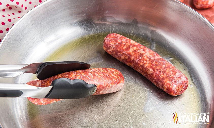 browning sausages in a stainless steel pan