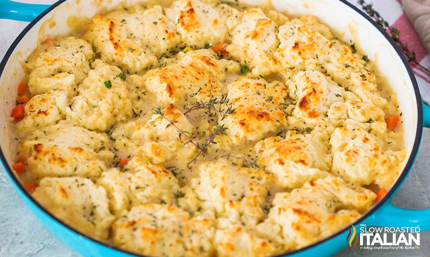 chicken pot pie in dutch oven topped with biscuits and herbs