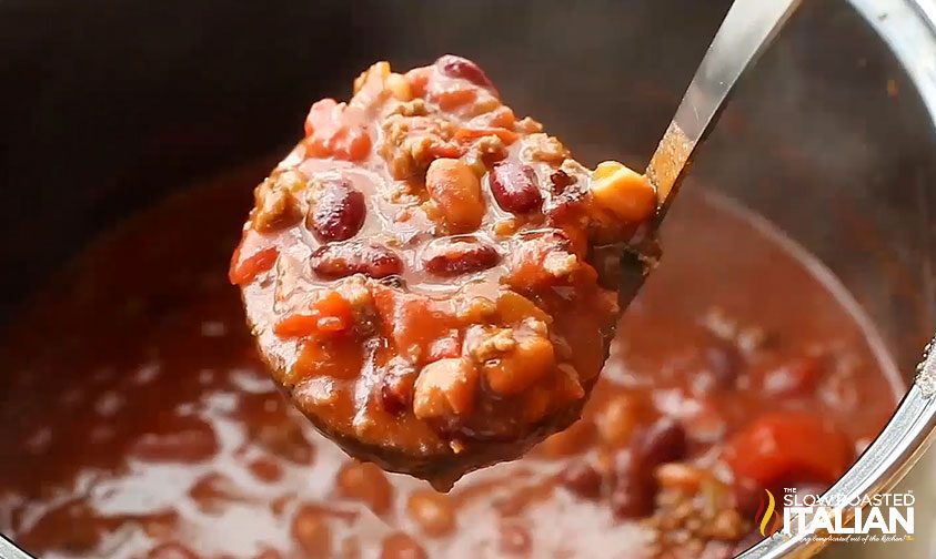 lifting a ladle of homemade chili out of a pot