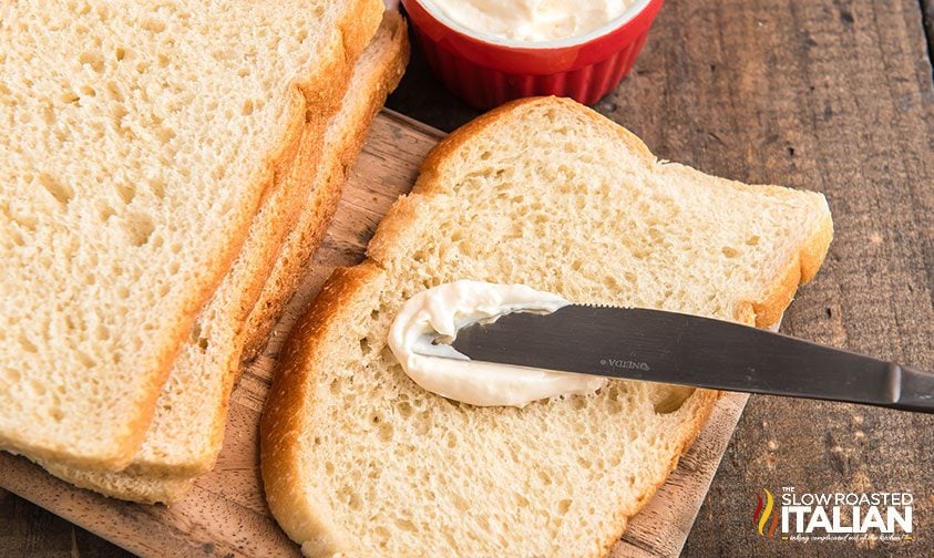 spreading mayonnaise on bread for grilled cheese