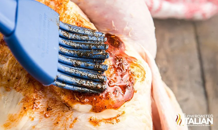 applying rub to whole chicken with basting brush
