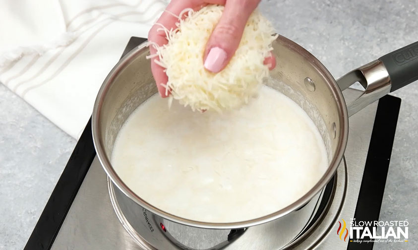 sprinkling grated cheese into half and half alfredo