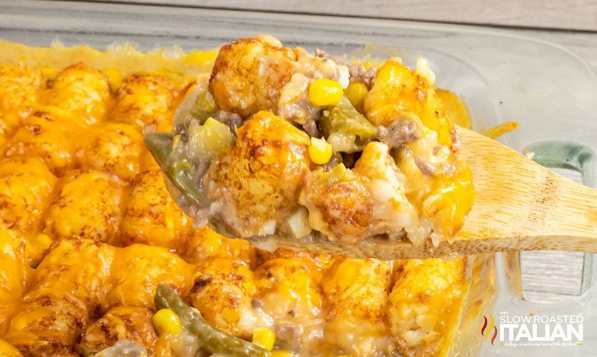 scooping hamburger tater tot casserole out of baking dish