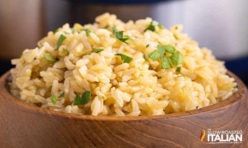 close up: wooden bowl of brown rice topped with parsley