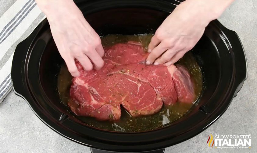 submerging beef roast in liquid in slow cooker