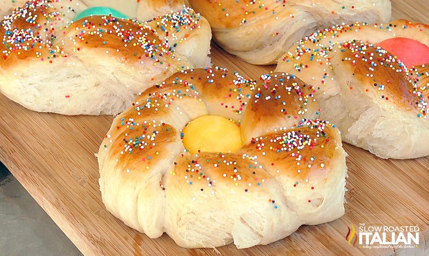 italian easter bread with colored egg in center topped with sprinkles