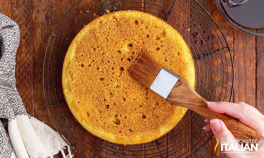 brushing espresso syrup over cake