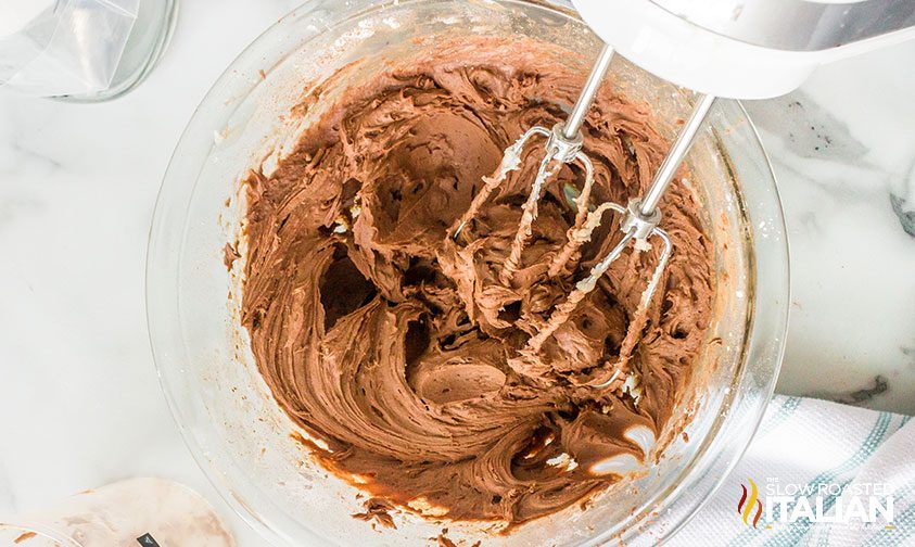 hand mixer resting in bowl of light chocolate frosting