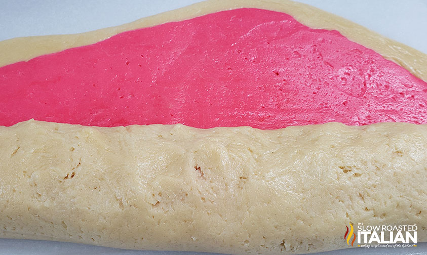 rolling plain and pink doughs together for pinwheel cookies