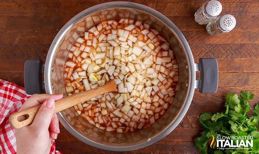 stirring pinto beans with onion and spices in pressure cooker