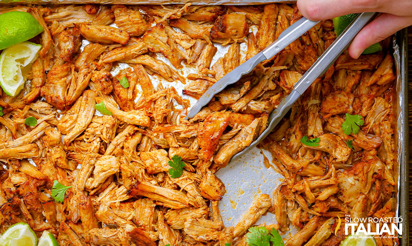flipping carnitas on sheet pan with tongs