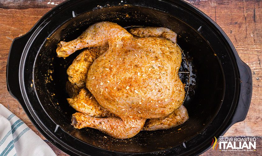 whole chicken in crockpot covered in seasonings