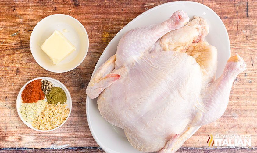 overhead: uncooked chicken next to bowls of butter and seasoning