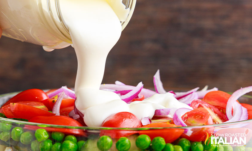 Pouring 7 layer salad dressing on 7 layer salad.