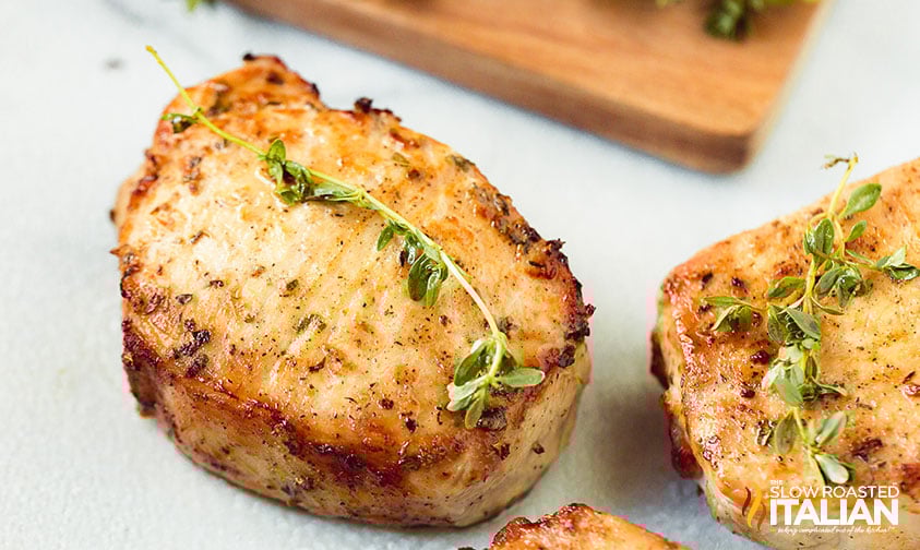 garnishing a cooked pork chop with small green sprig of herb
