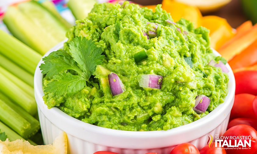 bowl of guacamole surrounded by veggies for dipping