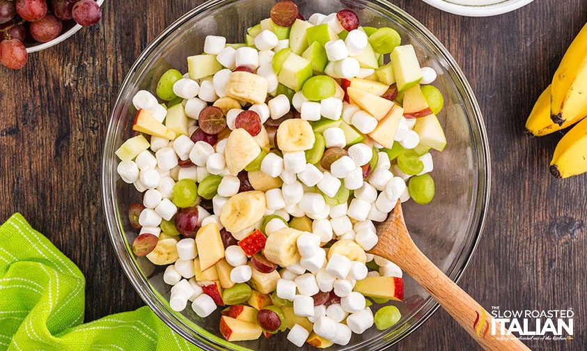 stirring mini marshmallows into fruit salad