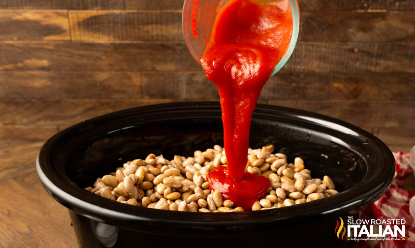 pouring ketchup over beans in crockpot