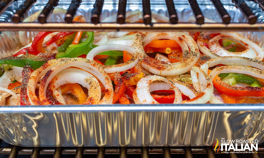 close up: pan of brats and veggies on pellet grill
