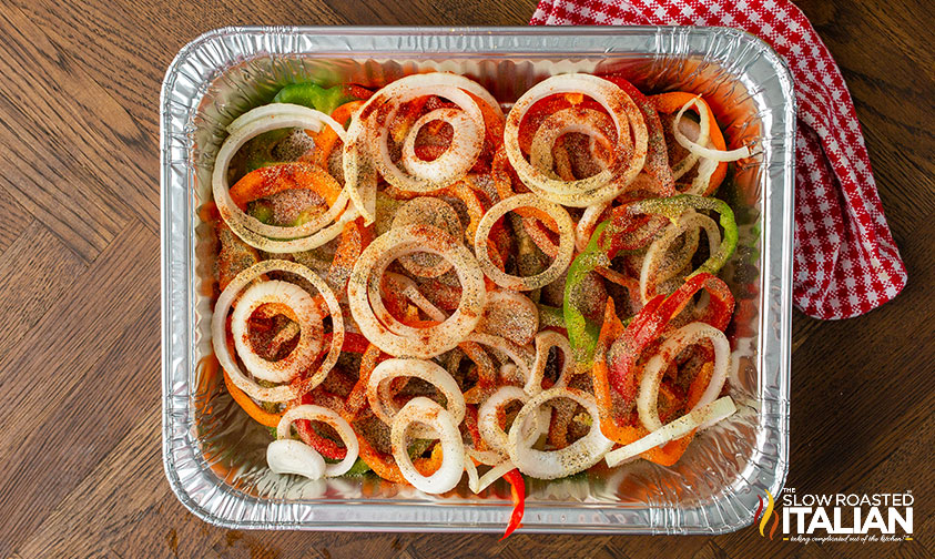 seasoned brats and veggies in a foil pan