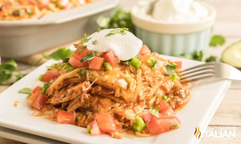 slice of cheesy chicken enchilada casserole topped with sour cream