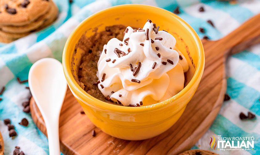cookie mug cake topped with whipped cream and sprinkles