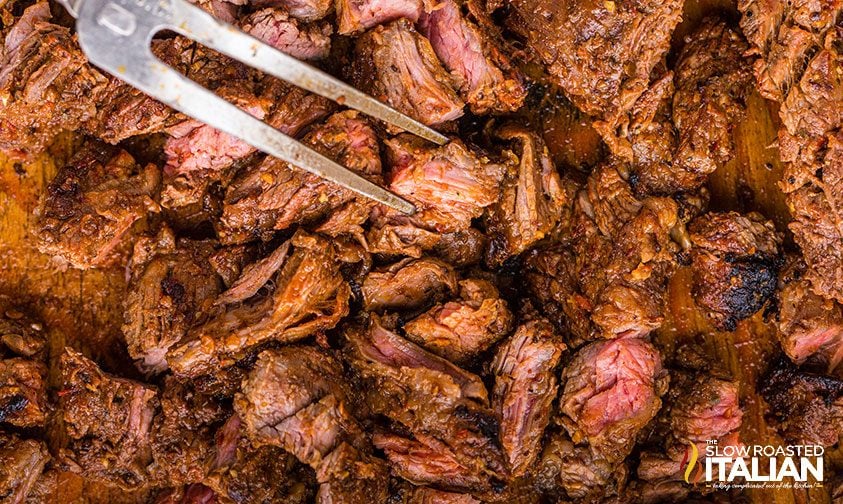 piercing pieces of chipotle steak with grill fork