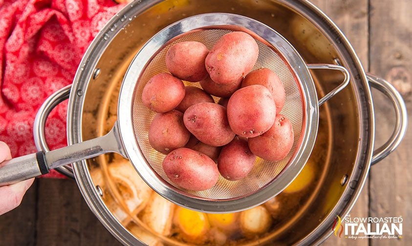 lowering red potatoes into large pot