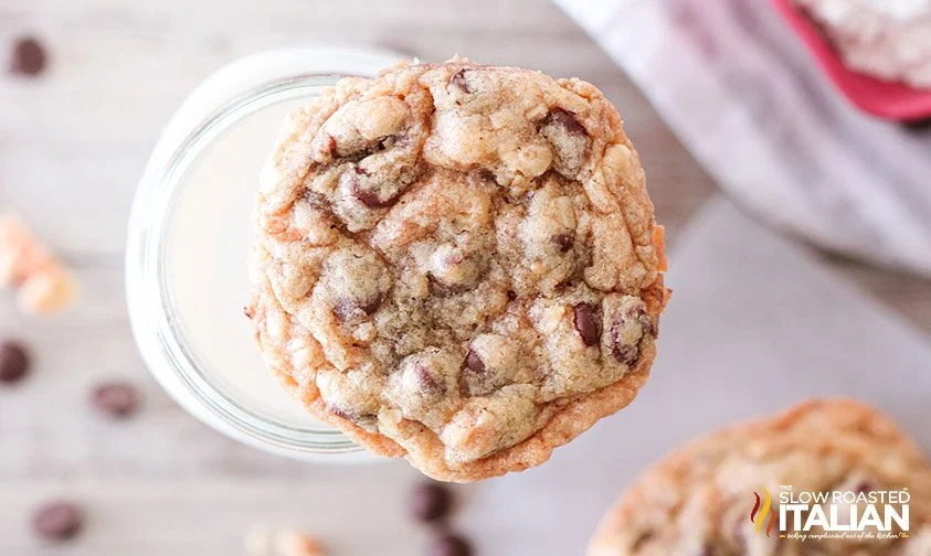 overhead: chocolate chip cookie resting on glass of milk