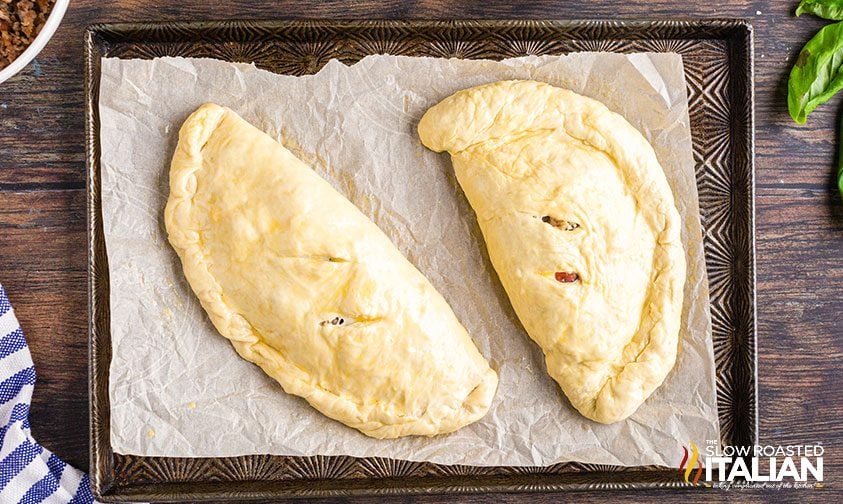 unbaked calzones on parchment lined baking sheet