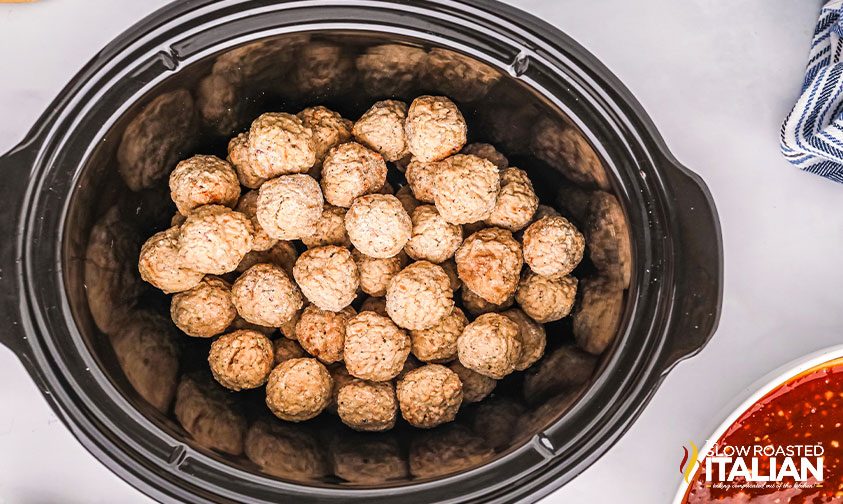 frozen meatballs in crockpot with bowl of sauce to the side